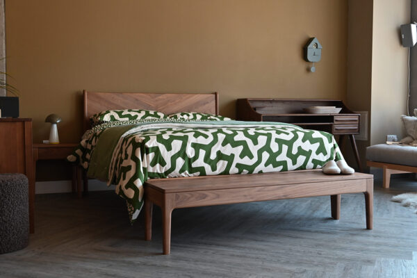 Green and white abstract bedding on solid walnut bed frame. Walnut bench and teak desk also in shot.