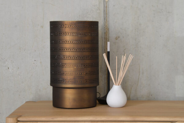 Large brass candle holder photographed on until with lamp and vase.