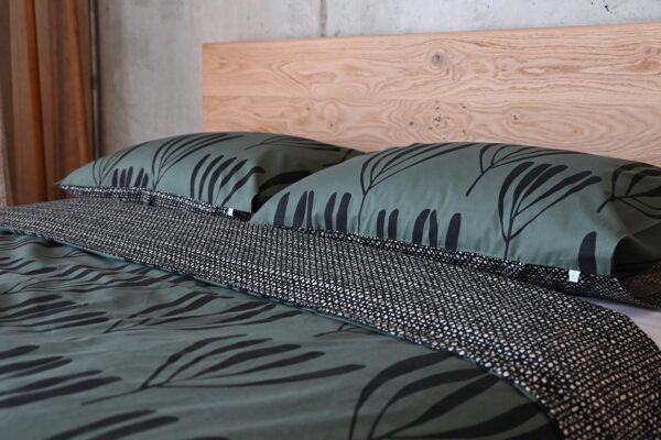 Green bedding with large black frond pattern. Duvet folded over to show black reverse.