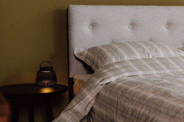 Bloomsbury bed with Amatheon Porcelain fabric headboard. Dressed with soft cotton stripe duvet set with fine dashed stripe pattern and modern lantern on bedside.