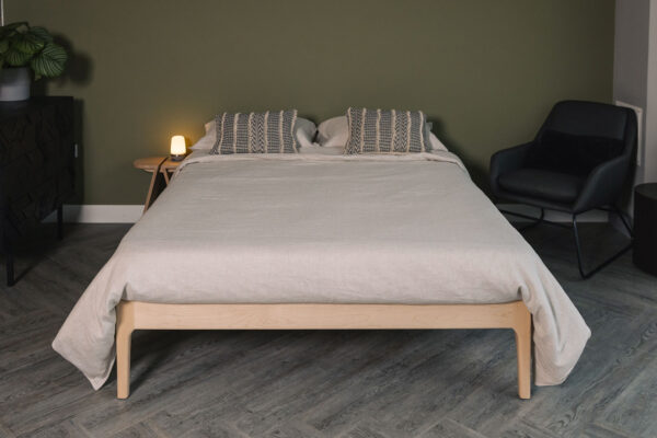 Camden bed base without a headboard in solid maple. Dressed with beige linen bedding and boho style cushions.