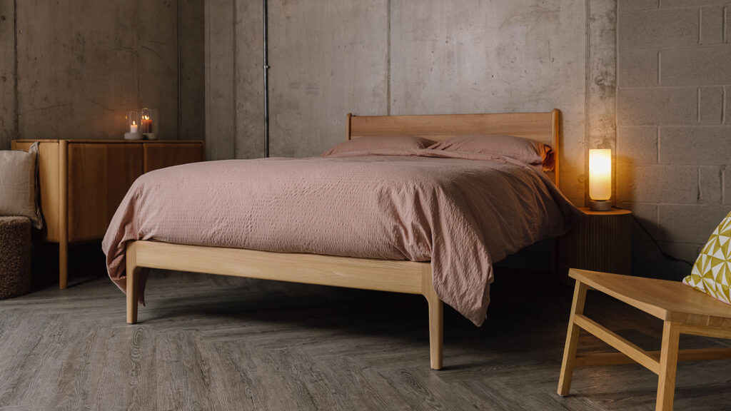 Scottish Elm Camden bed with seersucker bedding in dusty pink. Angled wide view.