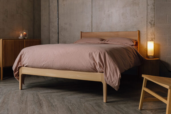Scottish Elm Camden bed with seersucker bedding in dusty pink. Angled wide view.