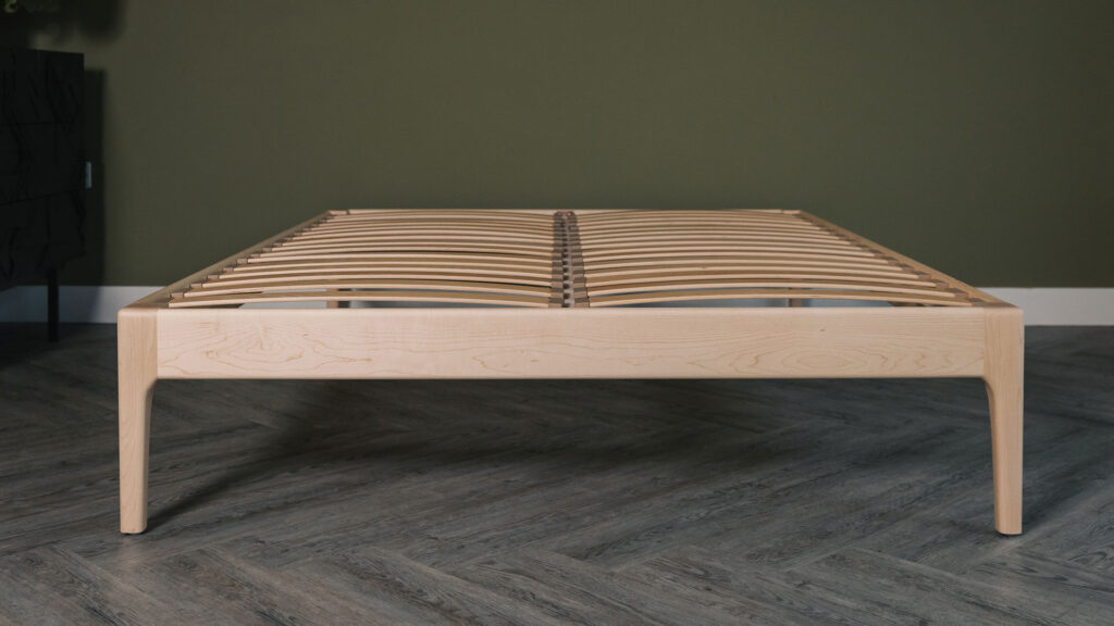 Camden bed without a headboard in solid maple without a mattress, viewed from the foot end.