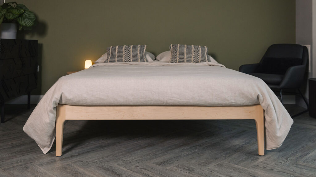 Front view of the Camden without a headboard in solid maple. Dressed with beige linen and boho style cushions.