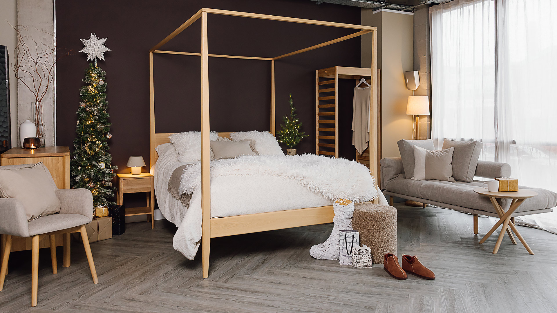 Relaxed bedroom scene with four poster bed, open wardrobe, lounger sofa bed, side table, chair, chest of drawers, bedside table and Christmas tree.