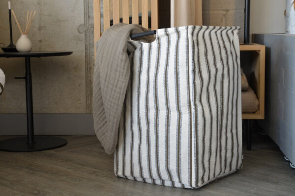 Khaki striped laundry bag photographed in bedroom scene.