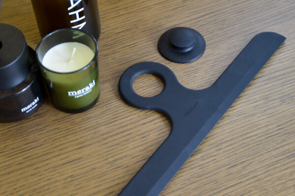 black shower wiper with hanger next to a candle and diffuser.