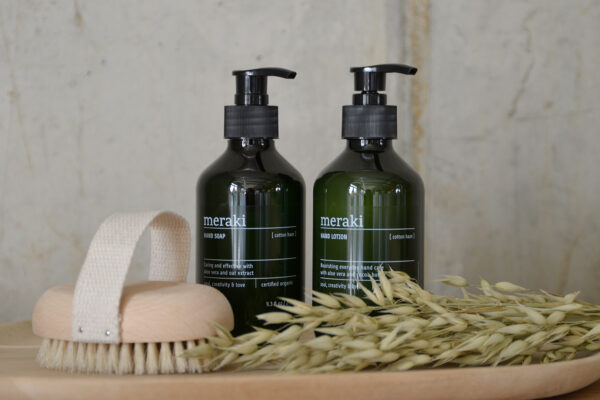 Bottles of hand soap and lotion photographed with nail brush on tray.