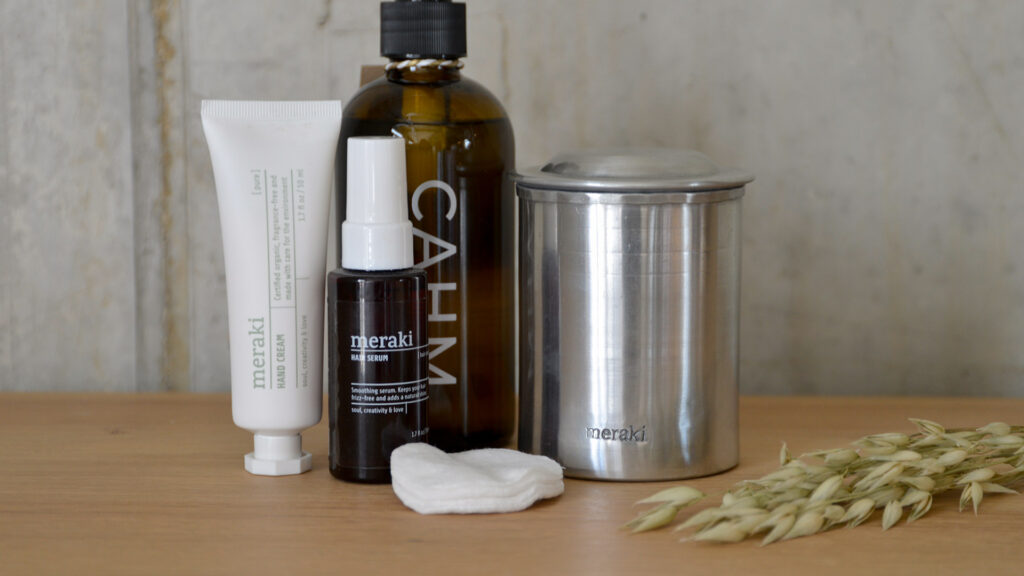 Silver Meraki storage jar with hand cream, hair serum, cleanser and cotton pads.