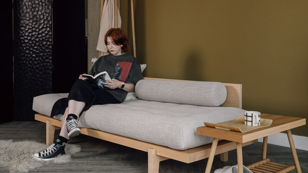 Model sat on Nara day bed with backrest.