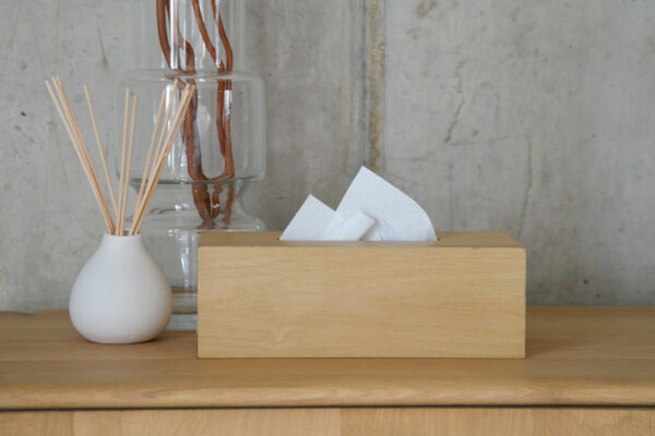 oak tissue box on table top next to clear vase.