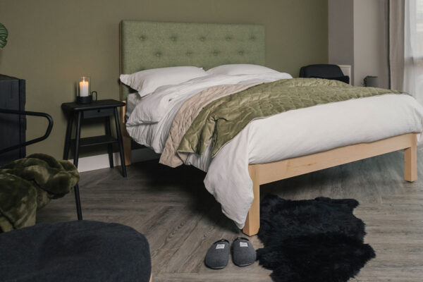 Skye upholstered bed with green headboard velvet throw and white muslin bedding