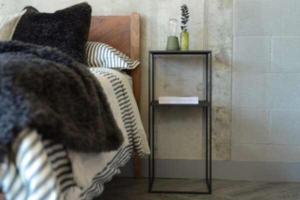 Zoomed out image of tall Fera table showing the full height of the item. Table is stood next to the Dalston bed in solid walnut.