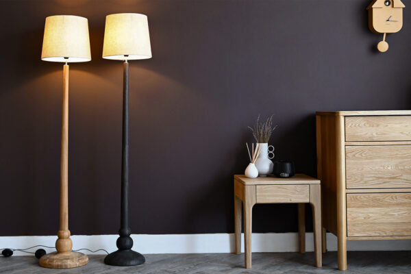 2 Floor lamps with wooden stands. Oak bedside table and chest of drawers to the side.