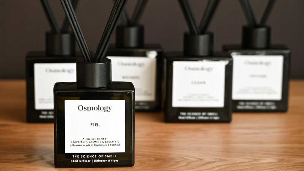 A close up of an Aery Osmology diffuser in the scent 'Fig'. Other scents are shown standing in the background, blurred.