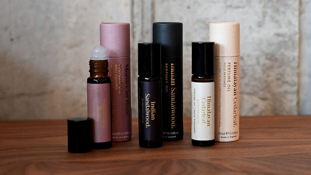 3 perfumed oils standing with packaging tubes behind them.