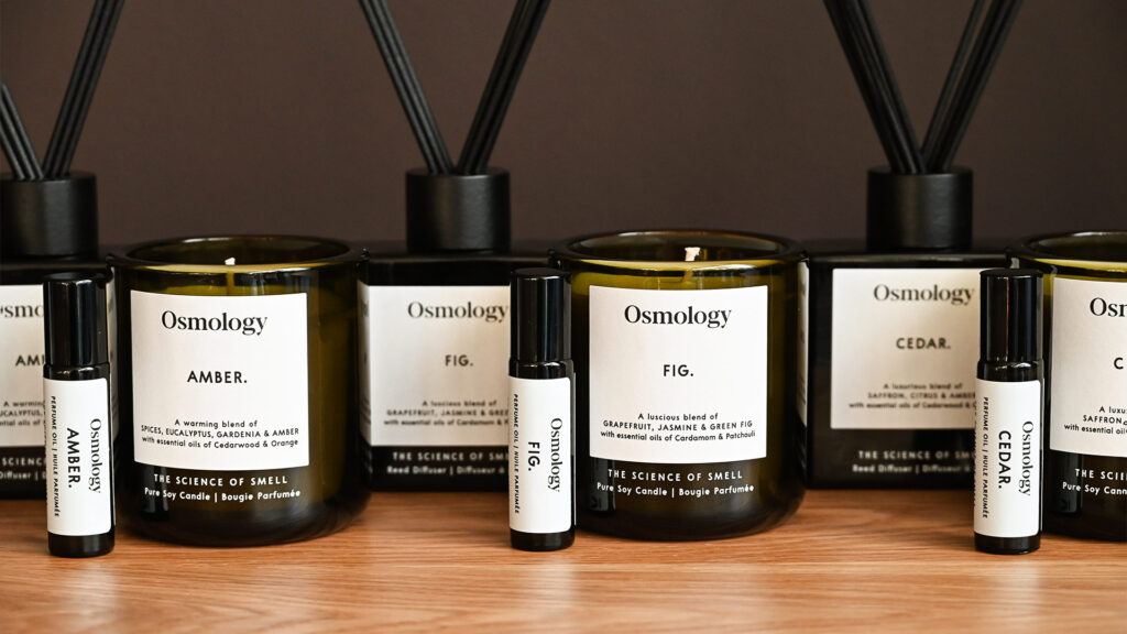 A close up, front-on image of the Aery Osmology diffusers, roll-on perfume oils and candles in the Amber, Fig and Cedar scents.