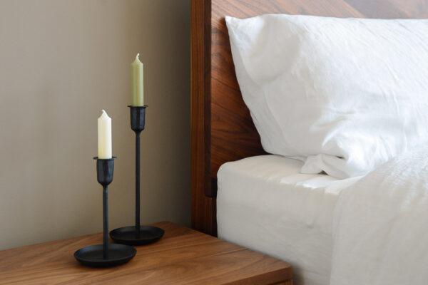 black metal candlestick holder two sizes on bedside table with white linen and walnut hathersage