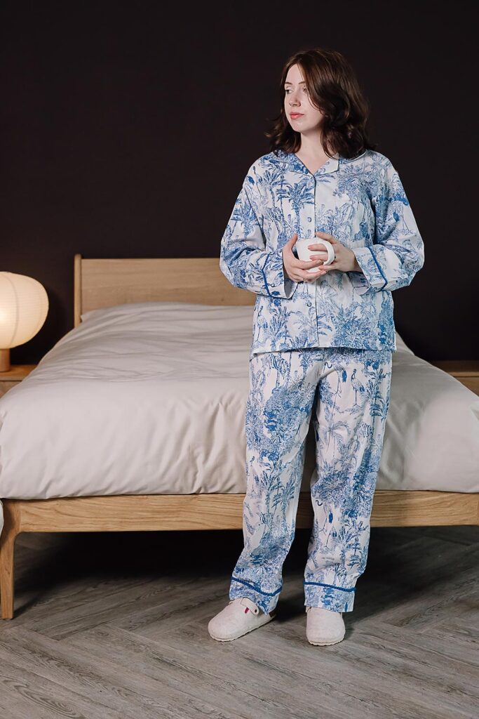 model wearing blue and white jungle print pyjamas holding a mug.