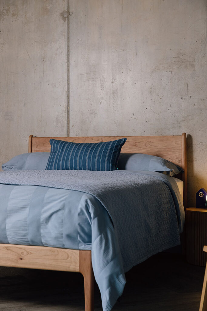 Cherry Camden with blue duvet cover, quilted bedspread and striped blue cushion.