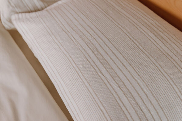Pillowcase from textured cotton duvet set with subtle beige stripes. Closeup.