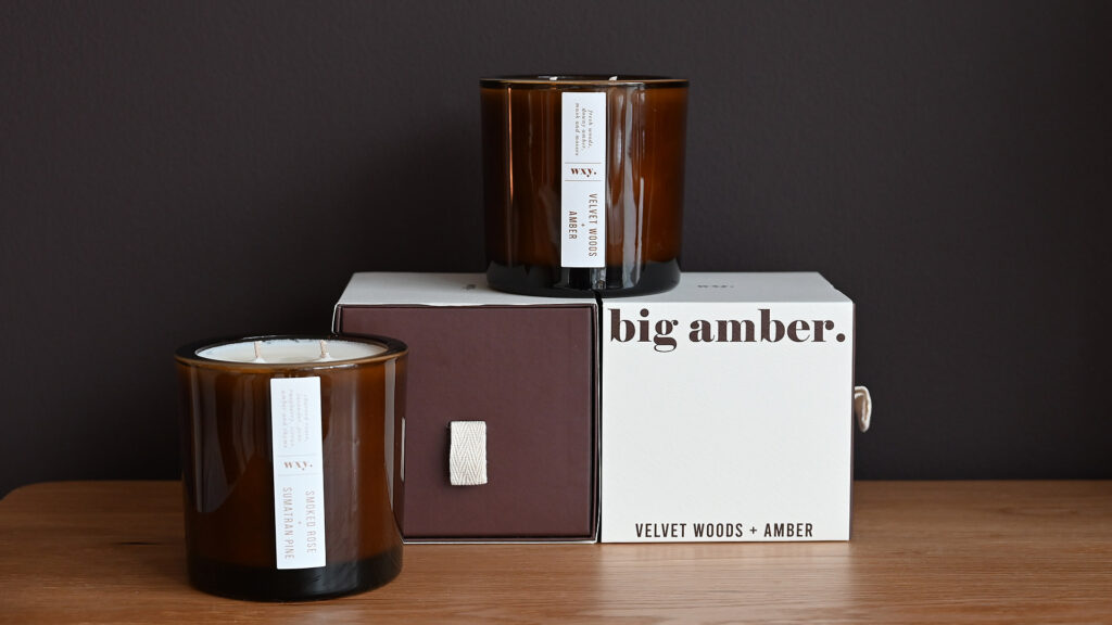 Large candles in amber glass jars from Wxy. Styled view with boxes.