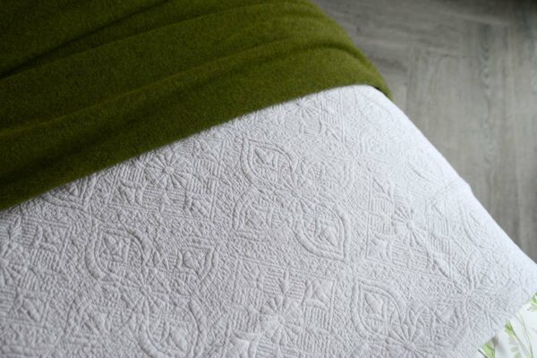 embroidered bedspread in white with green throw
