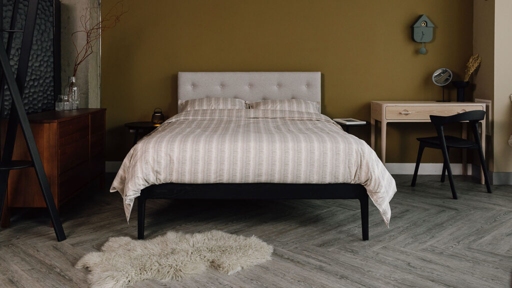 Bloomsbury bed in Black Oak with neutral duvet set. Room set view with white oak dressing table, black Bok chair from Ethnicraft and sheepskin rug.