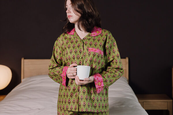 model wearing green and pink printed pjs holding a mug.