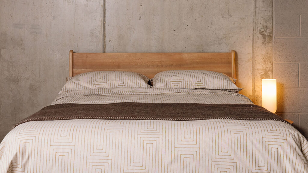 Scottish Elm Camden headboard detail with gold grid pattern cotton duvet set. A brown wool throw is laid over the duvet cover at the foot-end of the bed.