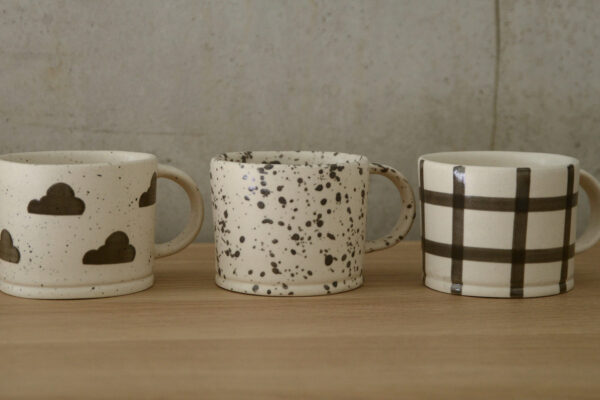 3 mugs, one with squares pattern, one clouds and one splashes.