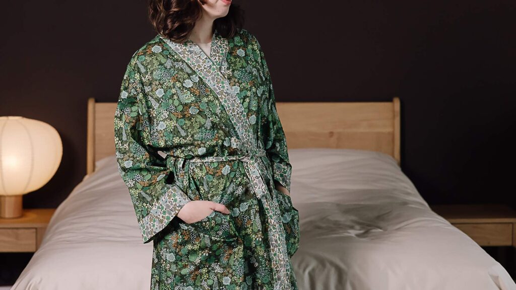 Model wearing green floral liberty print robe with hand in pocket.