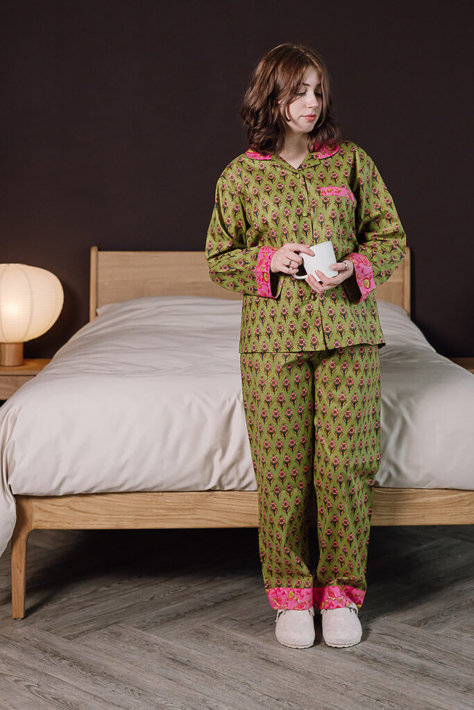 model wearing green and pink printed pjs holding a mug.