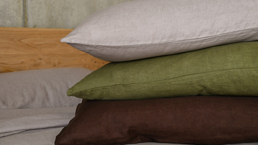 French linen bedding. Pillowcase stack showing three colours; mocha, olive green & chocolate brown.