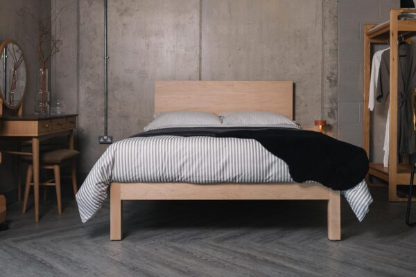 maple Bamford bed with grey striped bedding and black sheepskin
