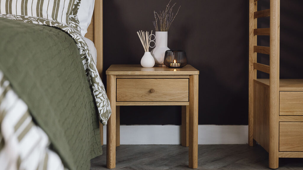 Oak bedside table with drawer. Vase, diffuser and candle holder on top.
