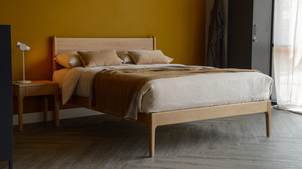 hand made, mid-century style oak camden bed with ecru and caramel bedding.