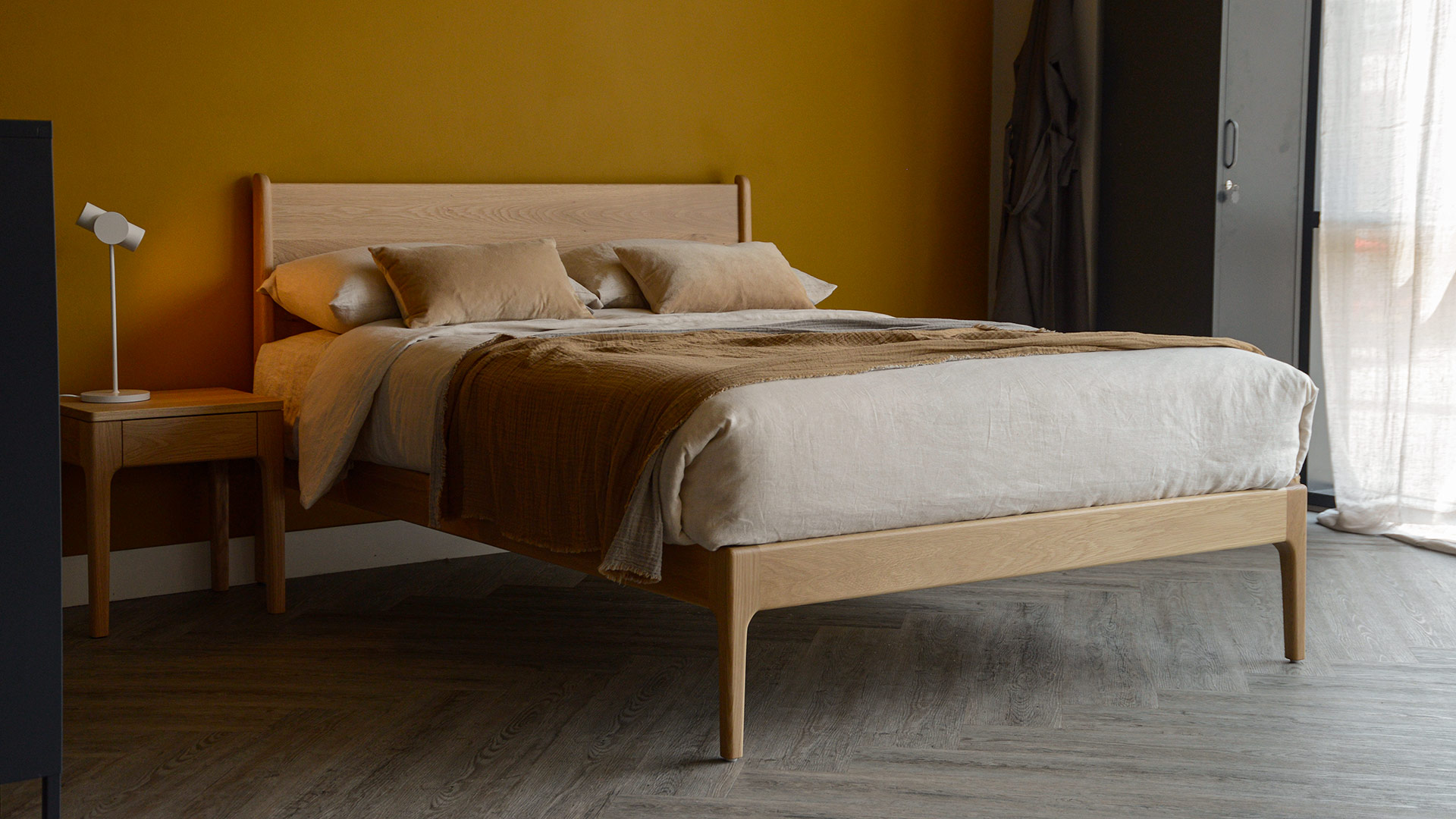 hand made, mid-century style oak camden bed with ecru and caramel bedding.