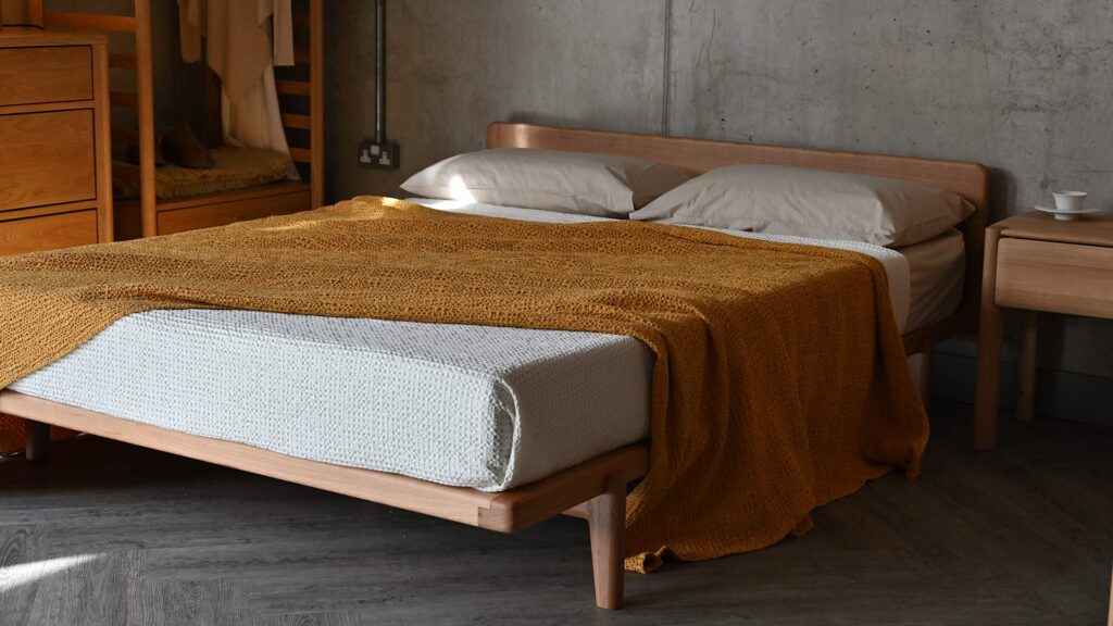A mustard yellow waffle bedspread on a solid cherry Osaka bed base.