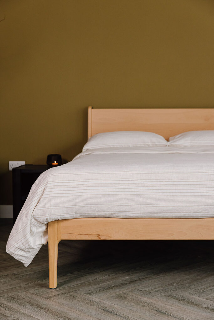 Beech Camden bed dressed with textured duvet set with subtle beige stripes. Portrait cropped view.