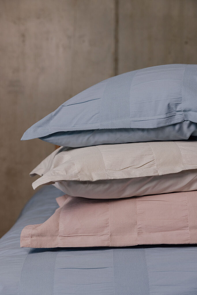 three pillows with full range of textured stripe pillowcases. From top to bottom: blue, ecru, pink.