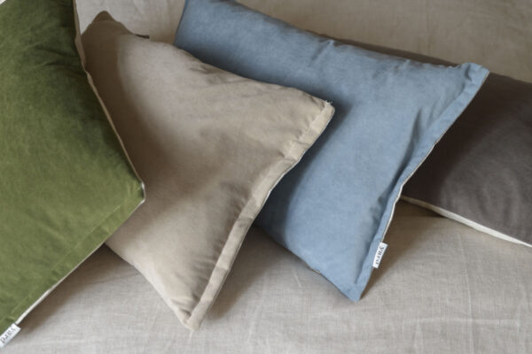grey, blue, ecru and green velvet cushions on bed.