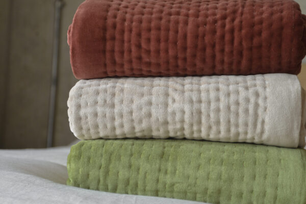 stack of three velvet quilts - wine red, almond and olive green.