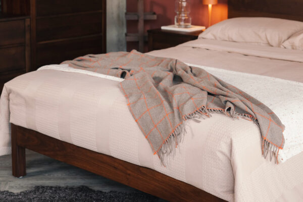 taupe cashmere throw with orange windowpane pattern on waffle stripe bedding