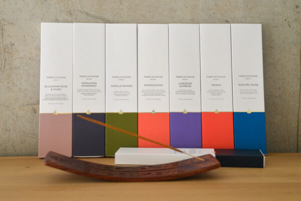 carved wooden incense holder with incense stick. Boxes of incense also in shot.
