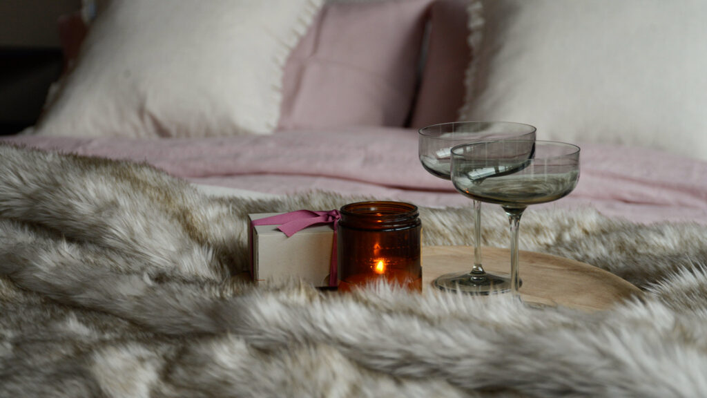 valentines day champagne glasses on bed with candle