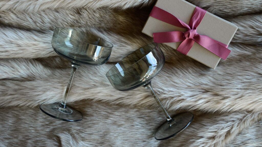 valentines day champagne glasses on faux fur bedspread with gift