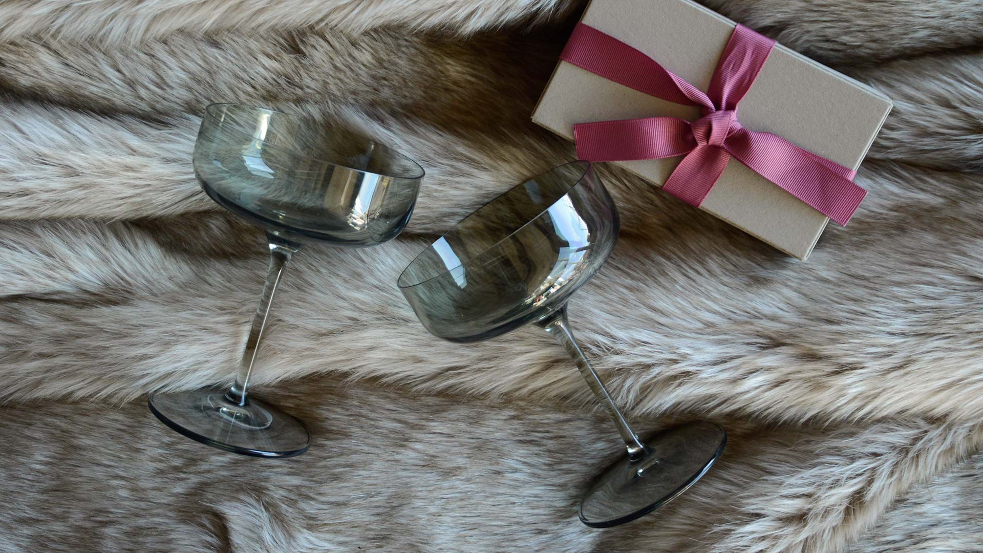 valentines day champagne glasses on faux fur bedspread with gift