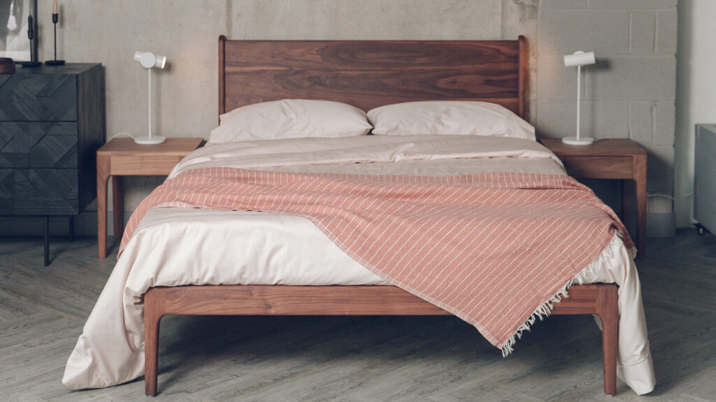 walnut Camden bed from front with shell colour bedding and striped throw.